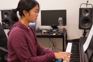 Gallery - Gallery Music School. teenage girl playing the piano in a music school, displaying her musical talent and dedication as she plays the piano keys with finesse and expression, guided by her music teacher, in pursuit of artistic growth and mastery. Adelaide piano instruction, piano lessons Adelaide, Adelaide piano classes, Adelaide piano tutoring, Linden Park SA piano instruction.