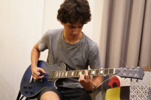 Gallery - Gallery Music School. Image of a teenager playing the guitar in a music school, demonstrating their skill and dedication as they strum the guitar strings with confidence and passion, guided by their music teacher, in pursuit of musical growth and artistic expression. Guitar classes Adelaide, Adelaide guitar lessons, guitar instruction Adelaide, Adelaide guitar teacher, guitar classes in Adelaide, guitar teacher Adelaide, guitar lessons Adelaide, Adelaide guitar instructor, guitar lessons in Linden Park SA.