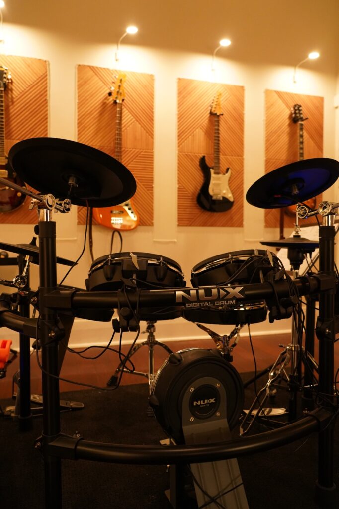 Close-up of an electronic drum kit with guitar wall at BeSharp Music School Adelaide