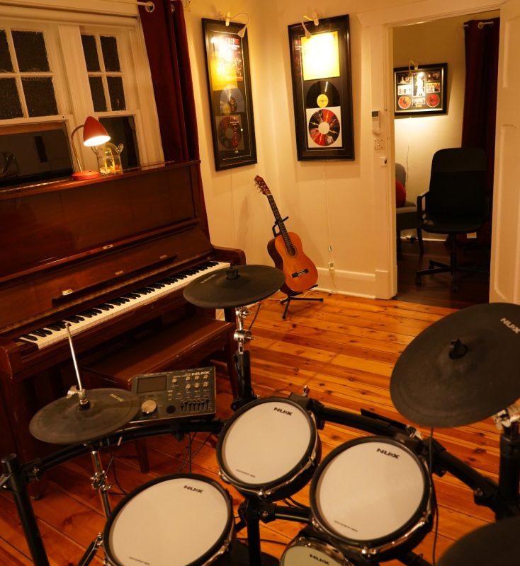 Electronic drum kit with upright piano and guitar in a BeSharp Music School room in Adelaide