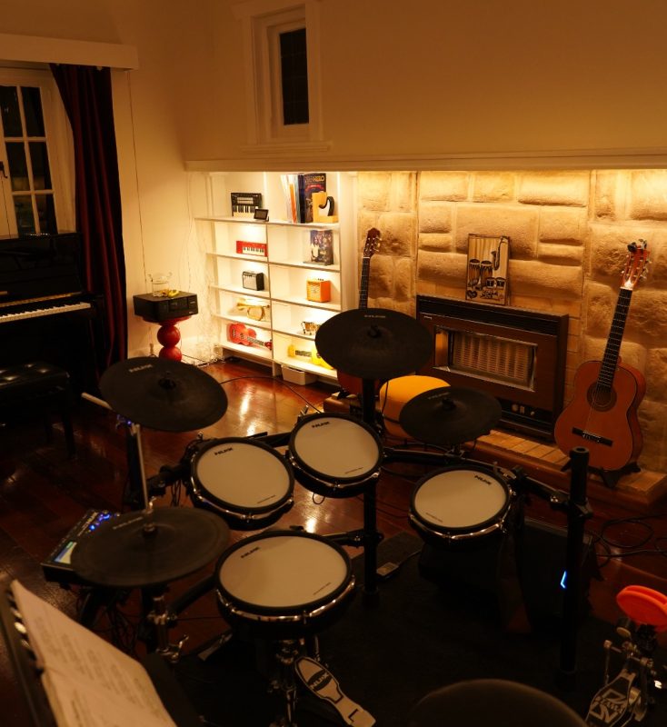 Electronic drum kit with upright piano and guitars in a BeSharp lesson room in Adelaide